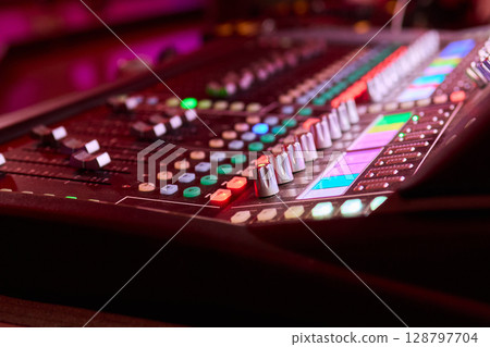 Closeup image of a hand mixing sounds on a control board, showcasing an audio technicians work Closeup image of a hand mixing sounds on a control board, showcasing an audio technicians work 128797704