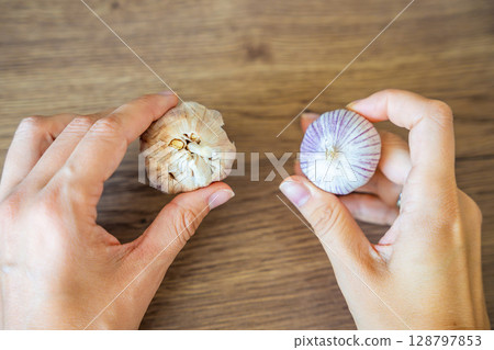 Female hands holding regular multi clove garlic in one hand and Chinese single clove garlic in the other. Concept of ingredient comparison and cooking choice. Female hands holding regular multi clove garlic in one hand and Chinese single clove garlic in the other. Concept of ingredient comparison and cooking choice. 128797853