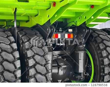 Close-up view of a bright green heavy-duty truck undercarriage showcasing tires and suspension system 128798538