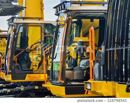 Heavy machinery lined up for inspection at a construction site during daylight hours Heavy machinery lined up for inspection at a construction site during daylight hours 128798541