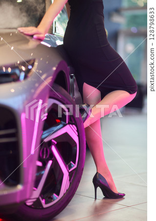 An Elegant Woman Gracefully Posing By a Luxury Car While Dressed in Chic and Stylish Attire An Elegant Woman Gracefully Posing By a Luxury Car While Dressed in Chic and Stylish Attire 128798633