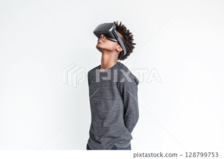 A teenager standing with VR glasses on, looking upward in awe 128799753