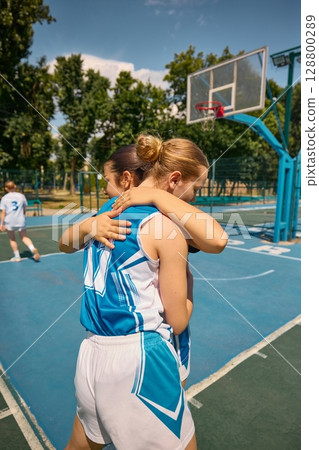 Team members hugging on an open-air basketball court during summer 128800289