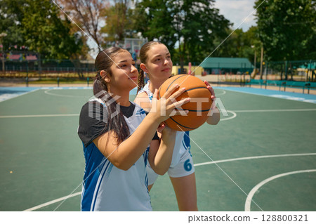 Female athletes training on an outdoor basketball court beneath a sunny sky Female athletes training on an outdoor basketball court beneath a sunny sky 128800321