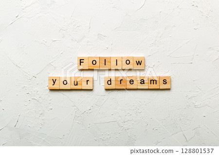 Follow your dreams word written on wood block. Follow your dreams text on cement table for your desing, Top view concept Follow your dreams word written on wood block. Follow your dreams text on cement table for your desing, Top view concept 128801537