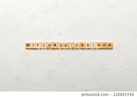 Microaggressions word written on wood block. Microaggressions text on cement table for your desing, concept Microaggressions word written on wood block. Microaggressions text on cement table for your desing, concept 128801548