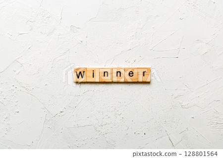 WINNER word written on wood block. WINNER text on cement table for your desing, concept WINNER word written on wood block. WINNER text on cement table for your desing, concept 128801564