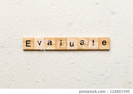 EVALUATE word written on wood block. EVALUATE text on cement table for your desing, concept EVALUATE word written on wood block. EVALUATE text on cement table for your desing, concept 128801595