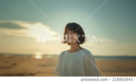 Woman walking on the beach at sunset 128801643
