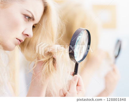Woman magnifying her split ends hair 128801848