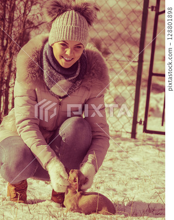 Woman playing with dog during winter Woman playing with dog during winter 128801898