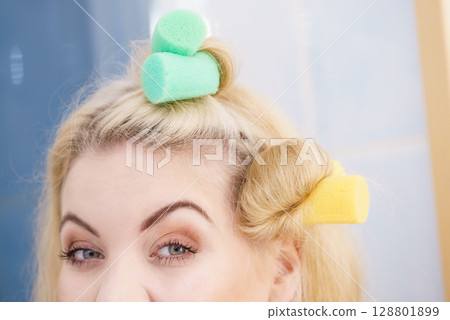 Blonde woman using hair rollers 128801899