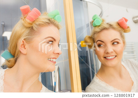 Blonde woman using hair rollers Blonde woman using hair rollers 128801917