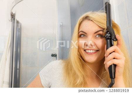 Woman using hair curler Woman using hair curler 128801919