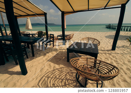 Beachside seating area with wooden furniture overlooking the turquoise sea in the popular summer travel destination in Koh Rong Sanloem, Sihanoukville, Cambodia Beachside seating area with wooden furniture overlooking the turquoise sea in the popular summer travel destination in Koh Rong Sanloem, Sihanoukville, Cambodia 128801957