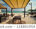 Tables under canopies on a sandy beach with a calm ocean backdrop in a public beach in Koh Rong Sanloem, Sihanoukville, Cambodia 128801958