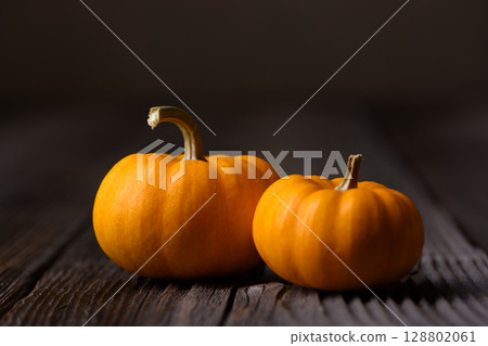 Two orange mini pumpkins on rustic wooden table close up Two orange mini pumpkins on rustic wooden table close up 128802061