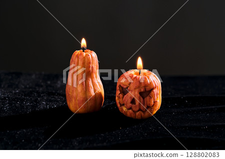 Halloween-style candles on a dark background. Festive decor. 128802083