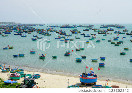 Colorful Basket and Fishing Boats Dot the Tranquil Bay of Mui Ne Under a Calm Sky in Vietnam Colorful Basket and Fishing Boats Dot the Tranquil Bay of Mui Ne Under a Calm Sky in Vietnam 128802242