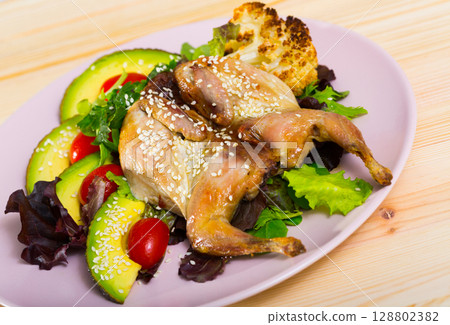 Photography of plate with quail-tobacco with sesame which served with salad of avocado and greenery Photography of plate with quail-tobacco with sesame which served with salad of avocado and greenery 128802382