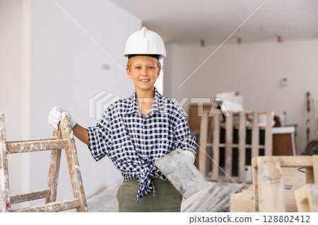 Preteen boy posing with trowel, home renovation 128802412