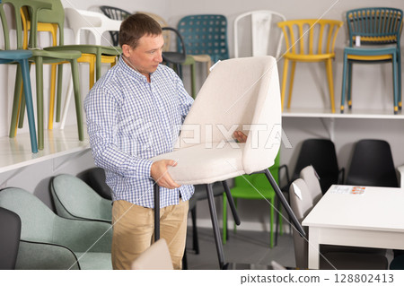 Man in furniture shop chooses chairs for her apartment 128802413