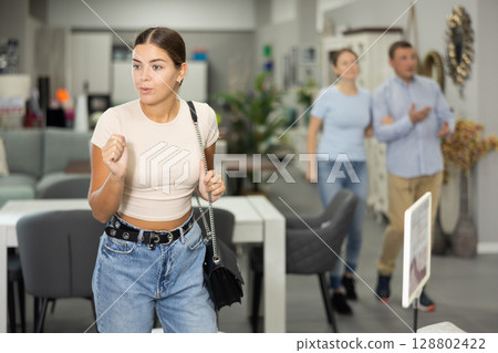 Interested young girl examining pieces of furniture in store 128802422