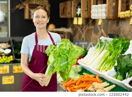 Female seller in uniform working in grocery shop, posing with salad 128802442