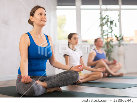 Mom with her family practices yoga in lotus position Mom with her family practices yoga in lotus position 128802443