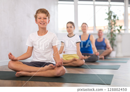 Teenage boy with her parents practices yoga in lotus position Teenage boy with her parents practices yoga in lotus position 128802450