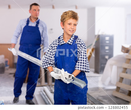 Smiling boy assisting his father in construction site Smiling boy assisting his father in construction site 128802455