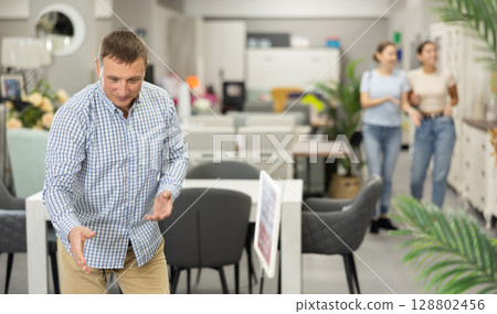 Man buyer choose dining table desk in furniture store showroom Man buyer choose dining table desk in furniture store showroom 128802456