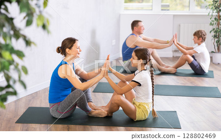 Happy mother and daughter practicing yoga poses Happy mother and daughter practicing yoga poses 128802469