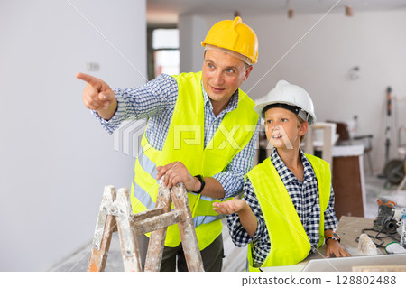 Young boy and his father discussing work plan in new apartment 128802488