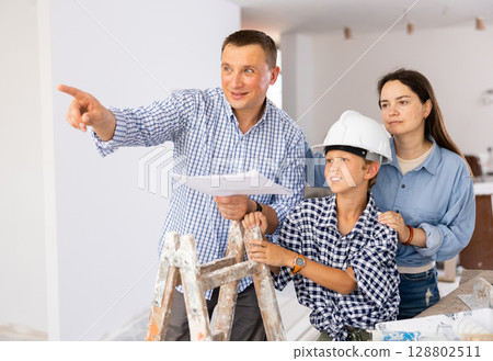 Parents and young son discussing work plan in construction site Parents and young son discussing work plan in construction site 128802511