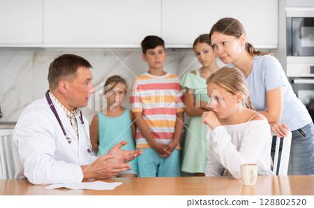Family doctor writes down complaints of the children of large family and writes out prescription 128802520