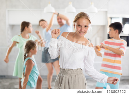 Behind cheerful girl, big family of parents, sisters, brother is rejoicing, dancing, having fun. 128802522