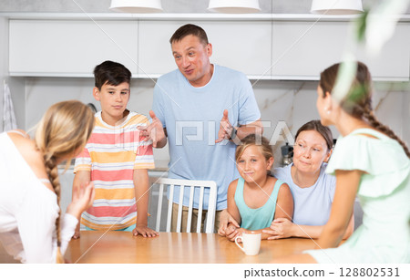 Friendly family gathered at table and cheerfully discuss past day. 128802531