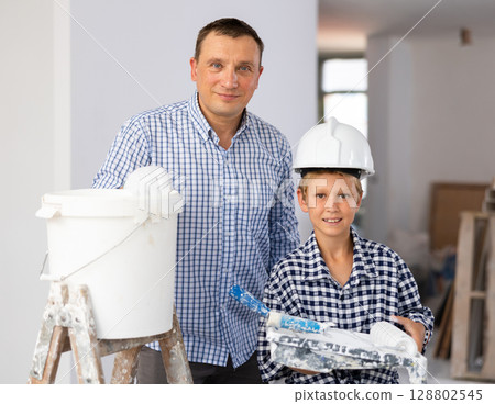 Portrait of positive young boy and father with paint rollers 128802545