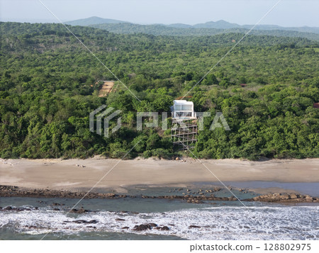 Modern architecture stands above beach in lush green landscape 128802975