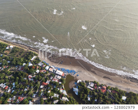 Coastal community with beach activities and serene waves on sunny day 128802979