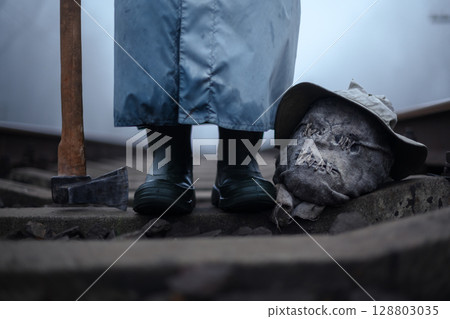 Creepy person with axe and severed head of scarecrow Creepy person with axe and severed head of scarecrow 128803035