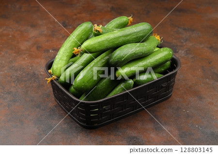 Fresh green cucumbers in a small wooden vegetable crate. Fresh green cucumbers in a small wooden vegetable crate. 128803145