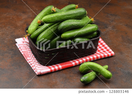 Fresh green cucumbers in a small wooden vegetable crate. Fresh green cucumbers in a small wooden vegetable crate. 128803146