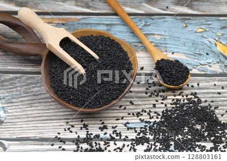 Black cumin seeds and essential oil with bowl and wooden shovel or spoon. Nigella Sativa in glass bottle. Organic herbal medicine for many diseases Black cumin seeds and essential oil with bowl and wooden shovel or spoon. Nigella Sativa in glass bottle. Organic herbal medicine for many diseases 128803161