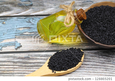 Black cumin seeds and essential oil with bowl and wooden shovel or spoon. Nigella Sativa in glass bottle. Organic herbal medicine for many diseases Black cumin seeds and essential oil with bowl and wooden shovel or spoon. Nigella Sativa in glass bottle. Organic herbal medicine for many diseases 128803201