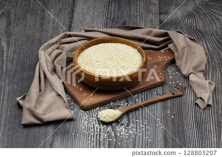 Top view closeup of freshly harvested white sesame in wooden bowl isolated on wooden background with clipping path. Top view closeup of freshly harvested white sesame in wooden bowl isolated on wooden background with clipping path. 128803207