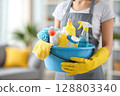 Woman in yellow rubber gloves holding blue bucket with cleaning products. Cleaning, housekeeping, household chores and hygiene concept and cleaning service 128803340