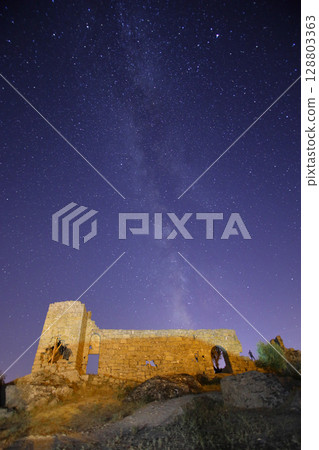 A view of the stars of the Milky Way with a mountain top in the foreground. Night sky nature summer landscape. Perseid Meteor Shower observation 128803363