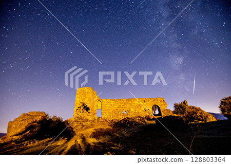 A view of the stars of the Milky Way with a mountain top in the foreground. Night sky nature summer landscape. Perseid Meteor Shower observation 128803364